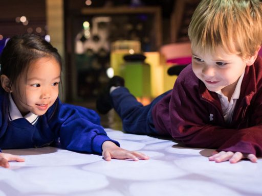 Two young children play with light patterns in Science Museum's Pattern Pod gallery.