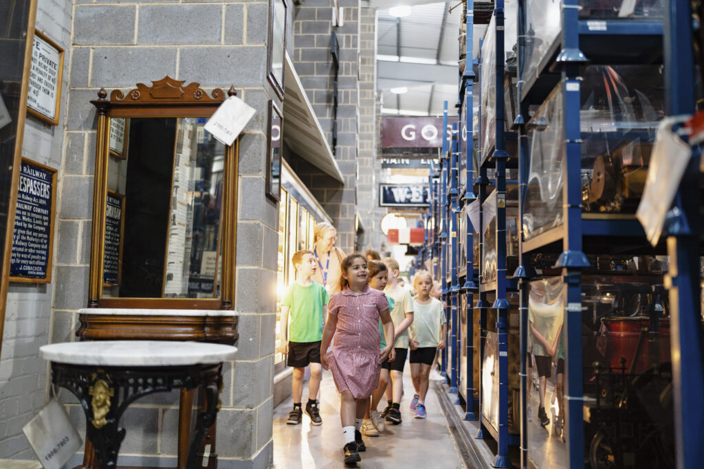 Children walk down a narrow museum corridor crammed full of objects from the railways past. They look in awe as they walk past model trains, models, old railway signs and so much more. 