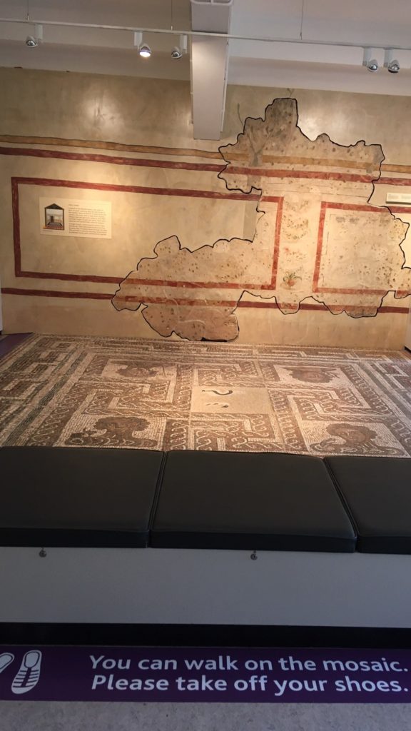The Four Season’s Mosaic with floor signage saying "You can walk on the mosaic. Please take off your shoes."
