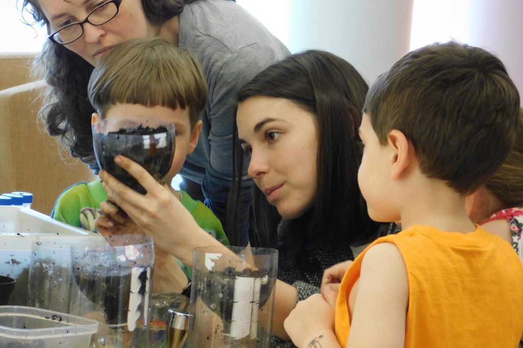 A student engaging a family in a soil activity.