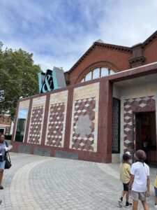 A brown building with white and beige tiles creating a pattern. At the top of the building a light blue V&A.